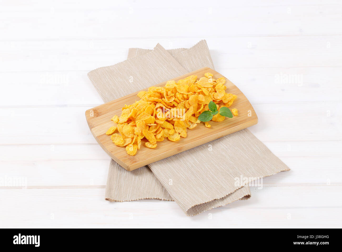 pile of corn flakes on wooden cutting board Stock Photo