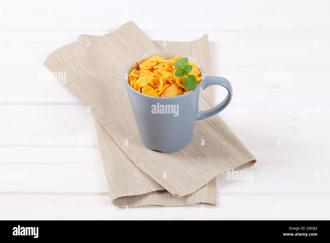 cup of corn flakes on beige place mat Stock Photo