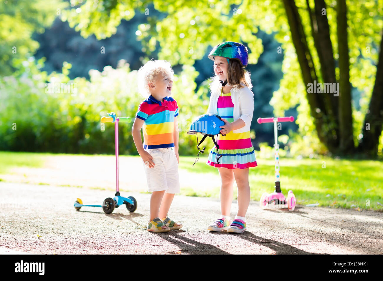 Children learn to ride scooter in a park on summer day. Preschooler