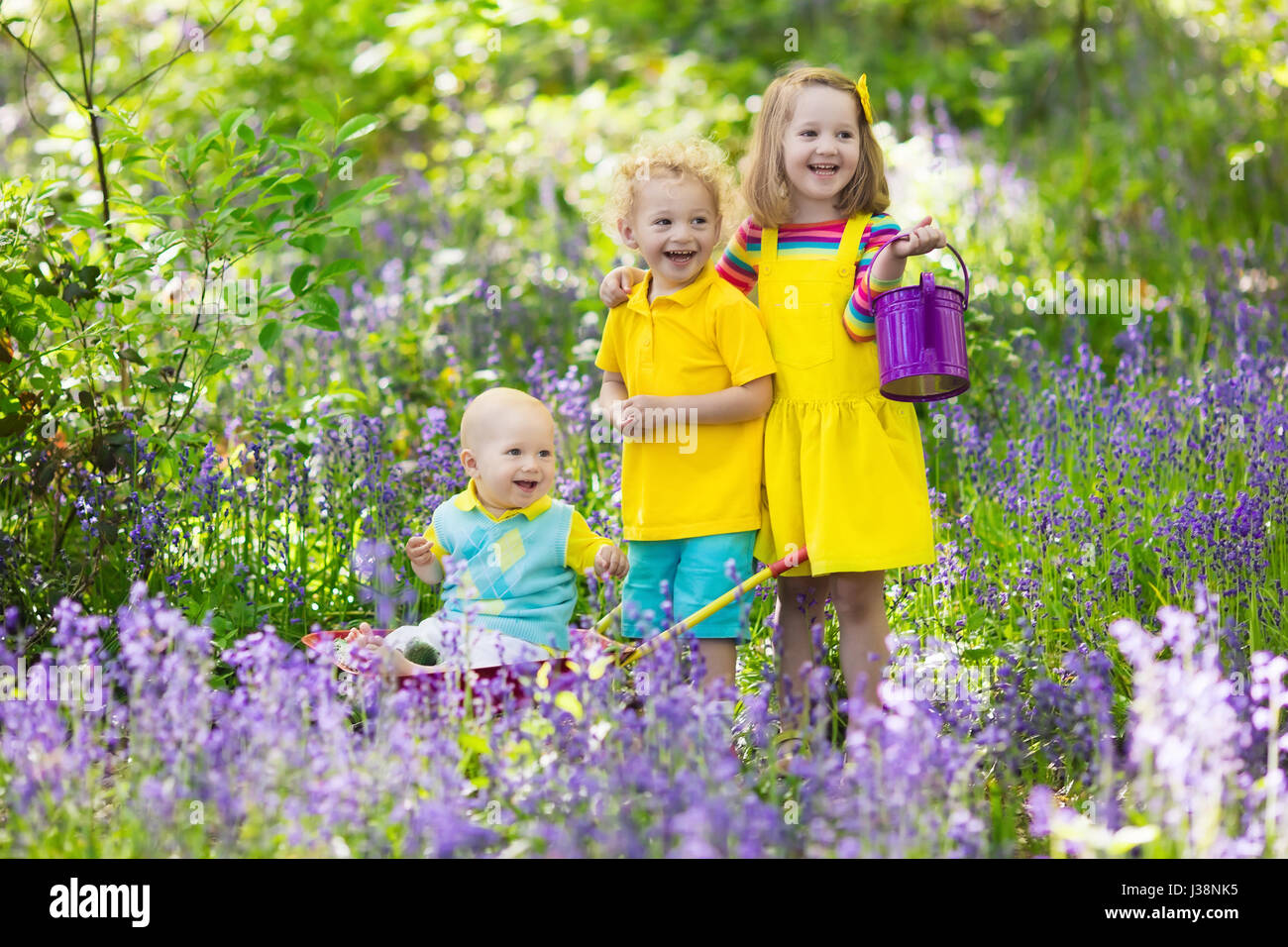 Kids With Bluebell Flowers Garden Tools And Wheelbarrow Boy