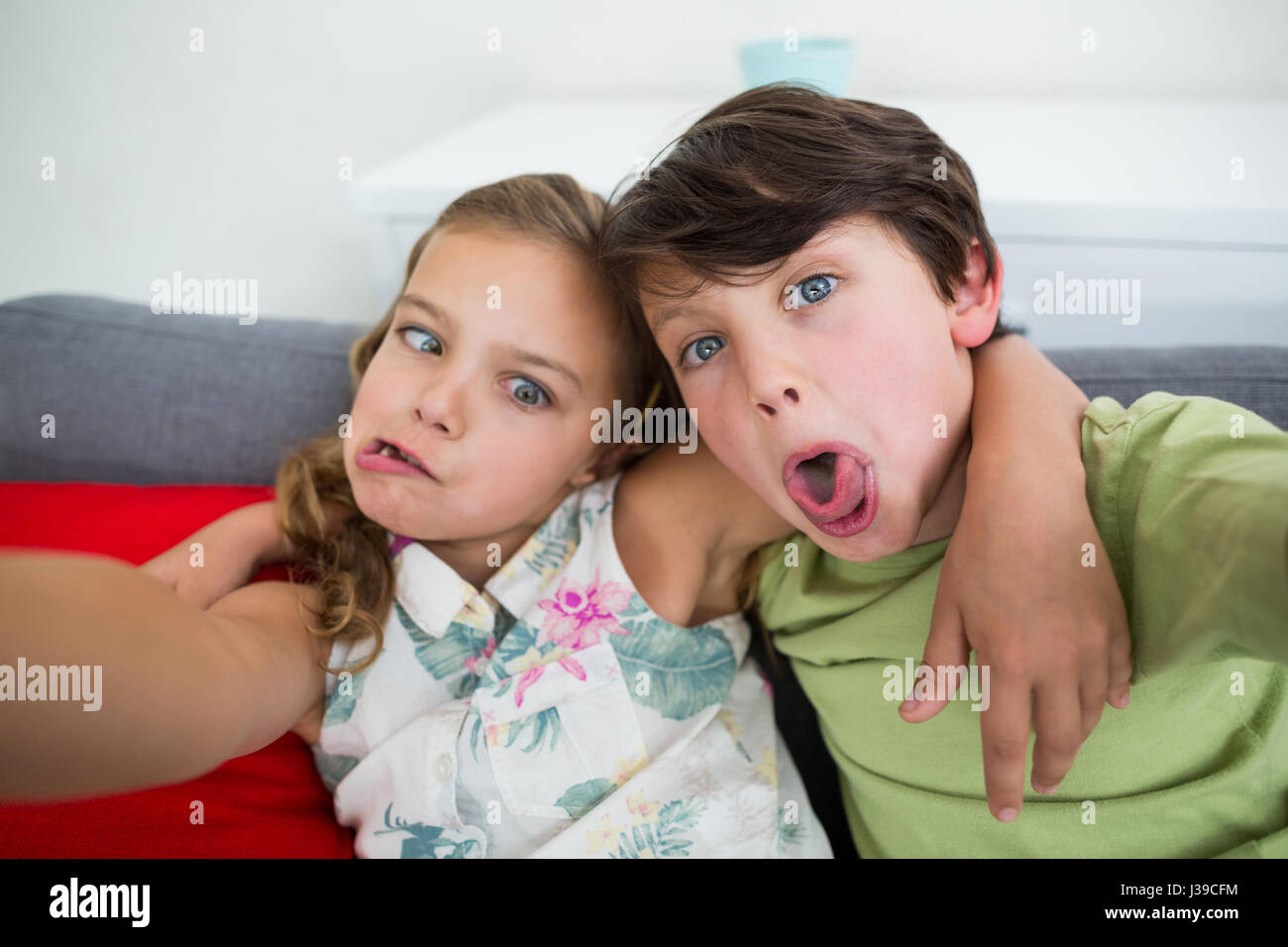 Siblings pulling funny faces in living room at home Stock Photo
