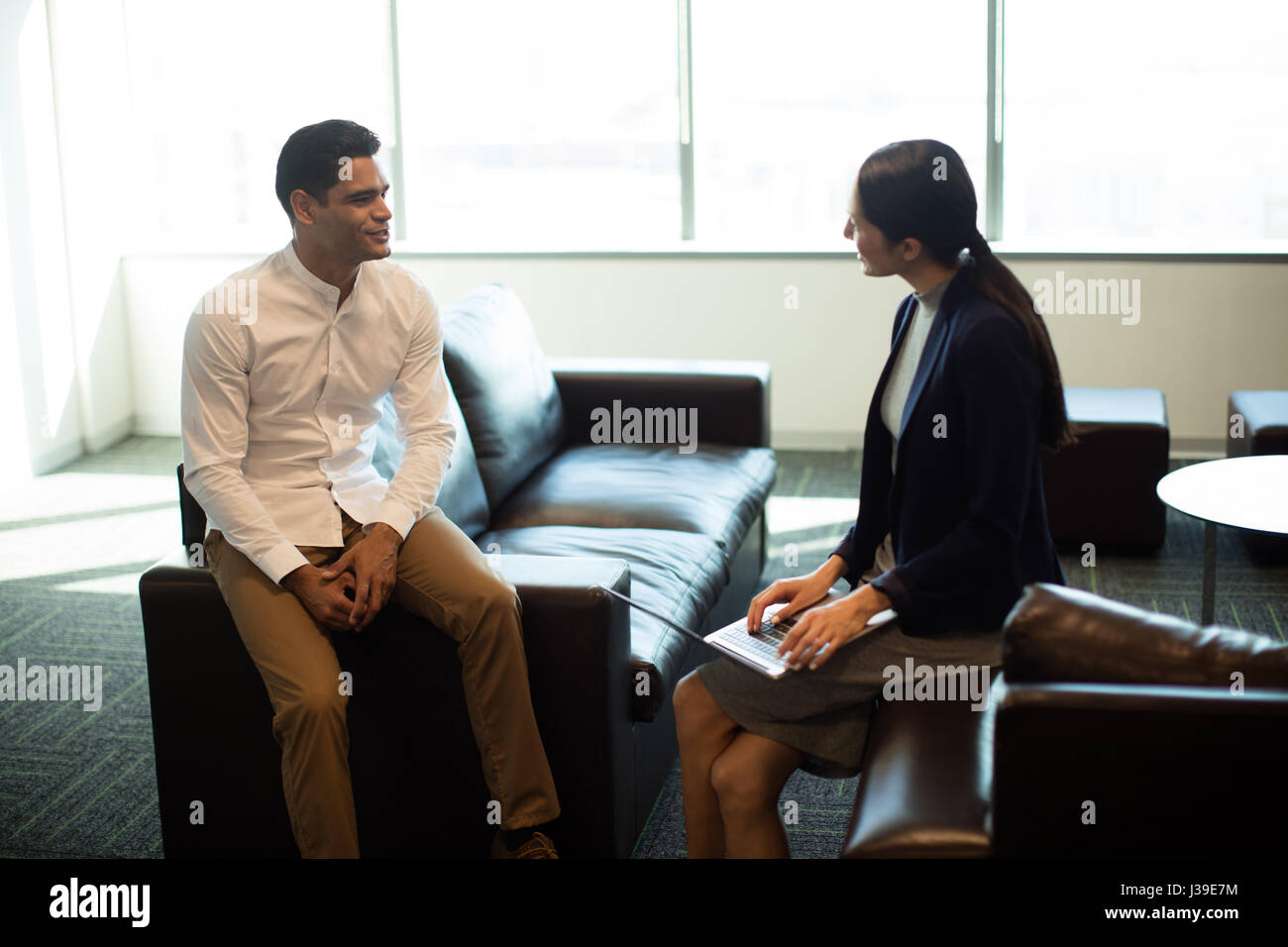 Businessman ineracting with female colleague while sitting on sofa at office Stock Photo
