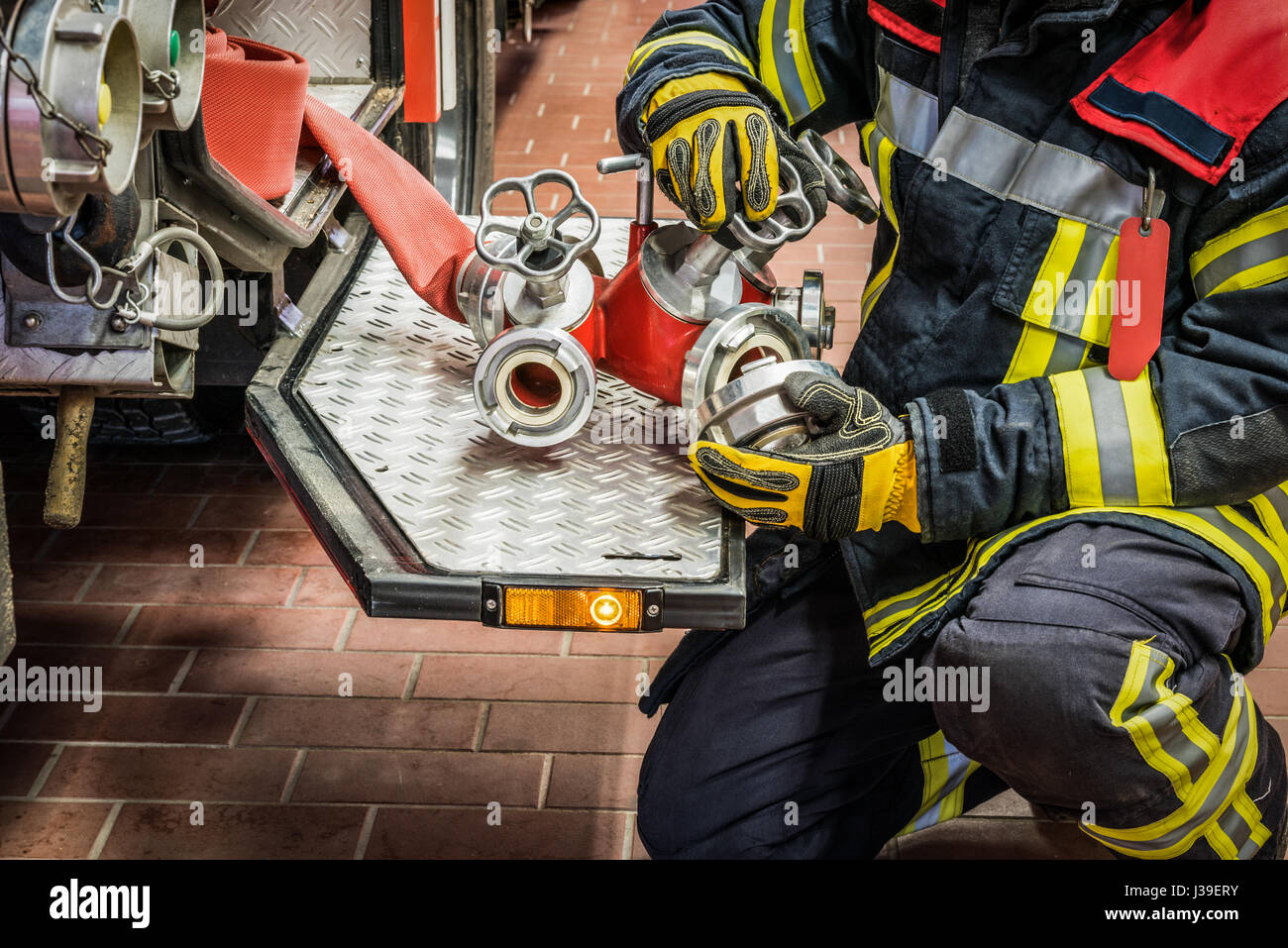 Firefighter in action with a fire hose on the fire truck - HDR Stock ...