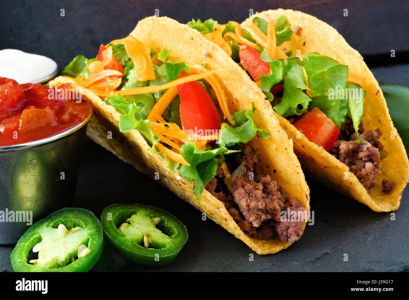 Hard shelled tacos with ground beef, lettuce, tomatoes and cheese close