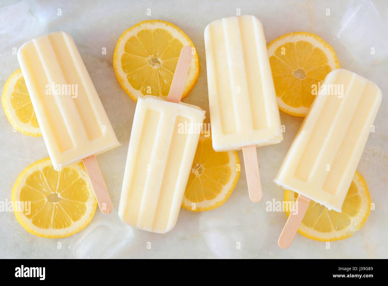 Healthy lemon yogurt popsicles with fresh lemon slices scattered on a
