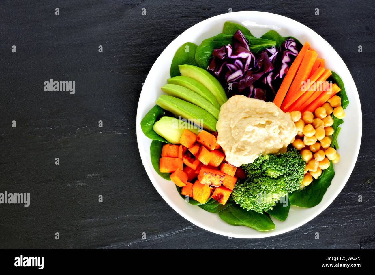 Healthy nourishment bowl with super-foods and fresh mixed vegetables, overhead view on dark slate Stock Photo