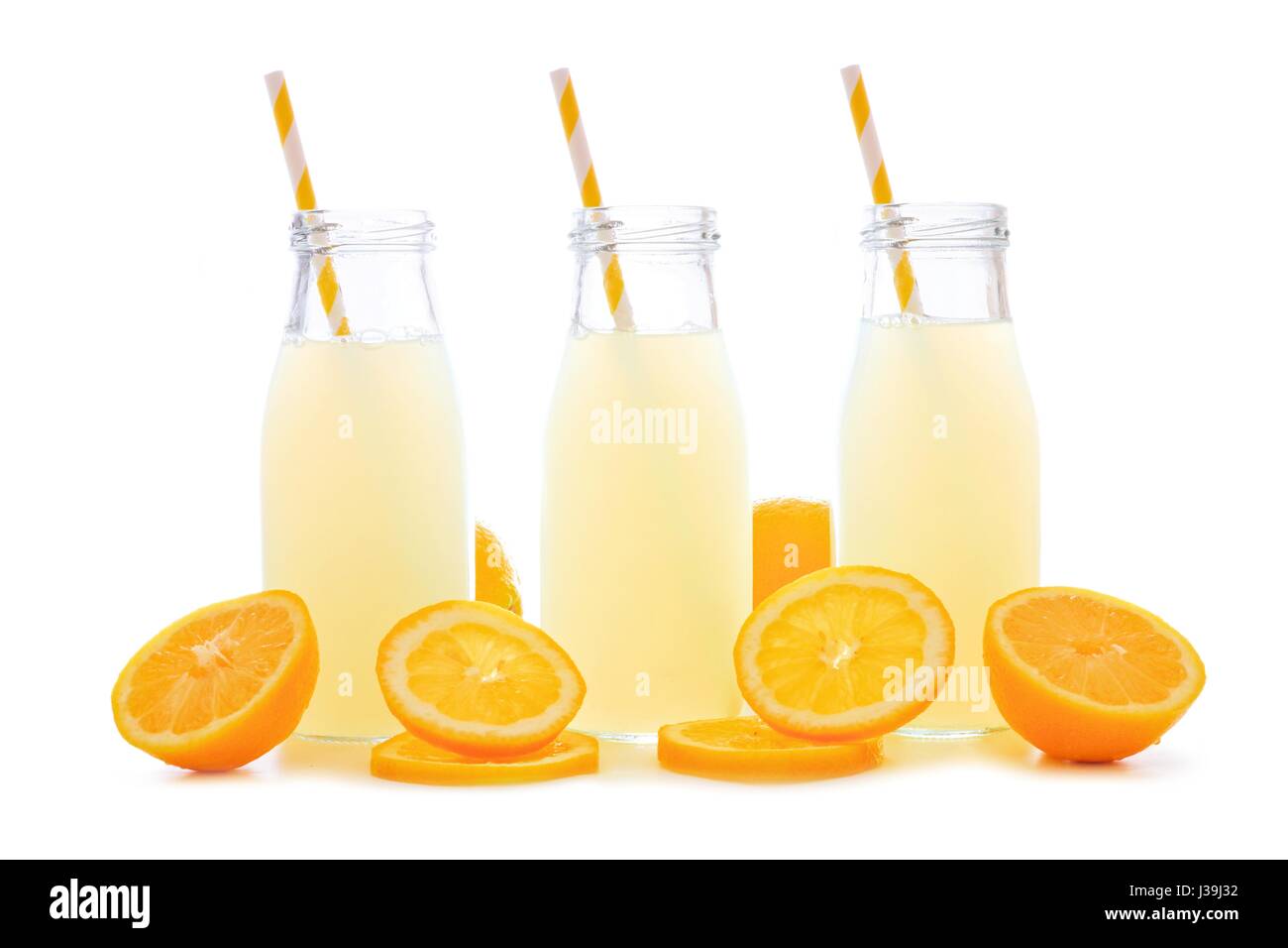 Three bottles of cold lemonade with lemon slices and straws isolated on a white background Stock Photo