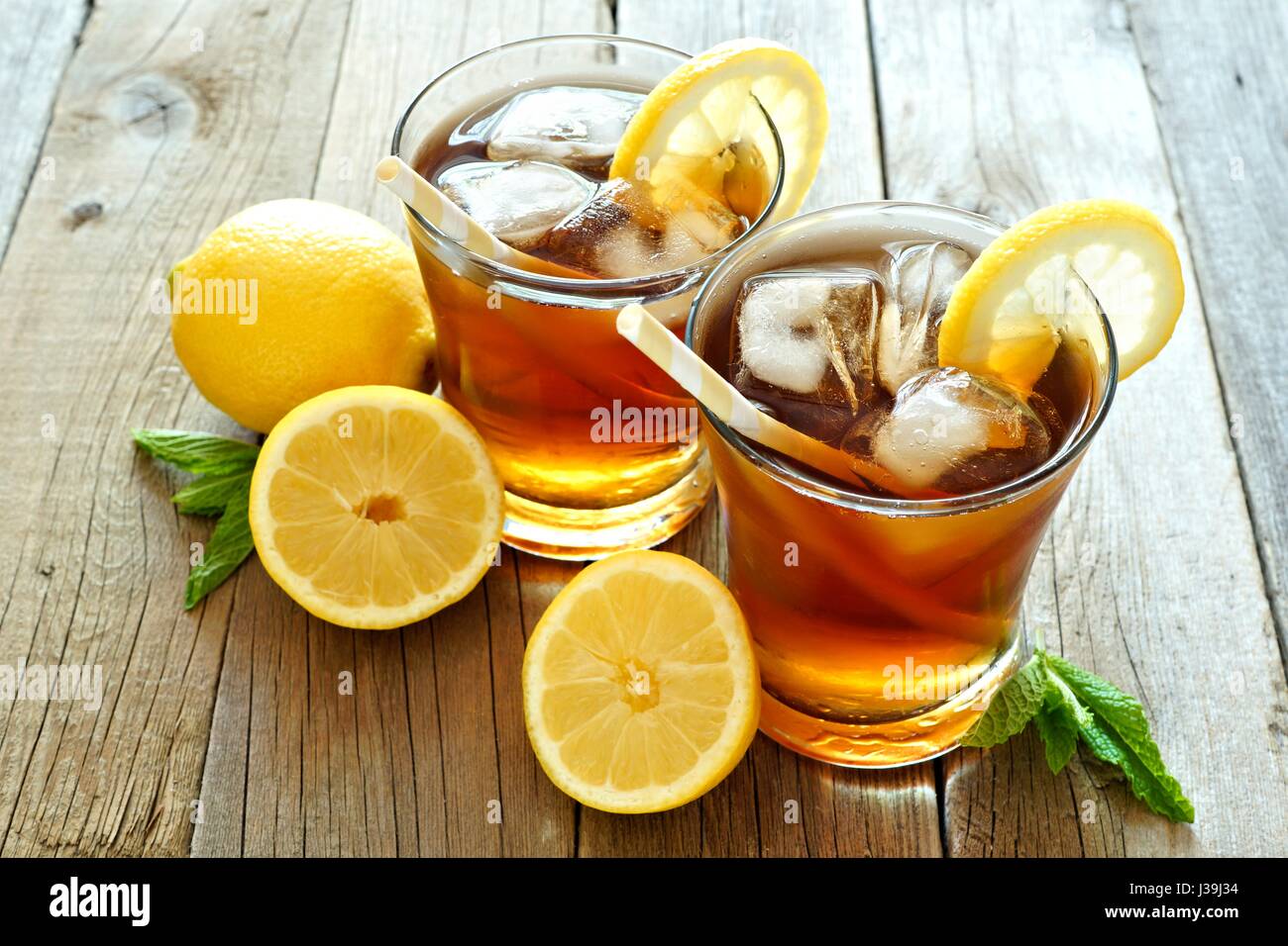 Two glasses of cold iced tea with lemon slices on a rustic wood background Stock Photo