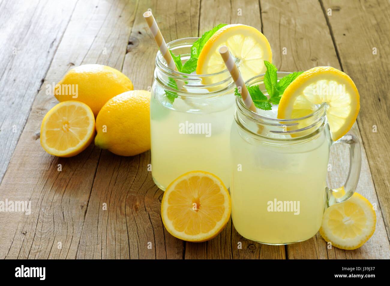 Two mason jar glasses of homemade lemonade on a rustic wooden background Stock Photo