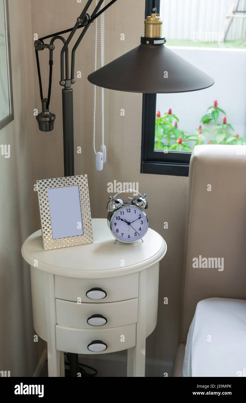 black lamp, picture frame and alarm clock on bedside table Stock Photo