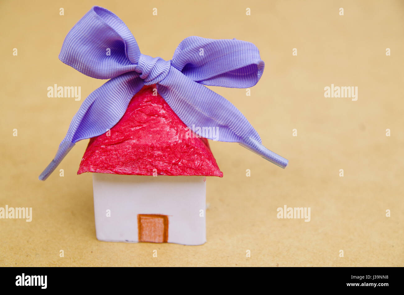 Little beautiful paper house with purple ribbon on wooden background Stock Photo