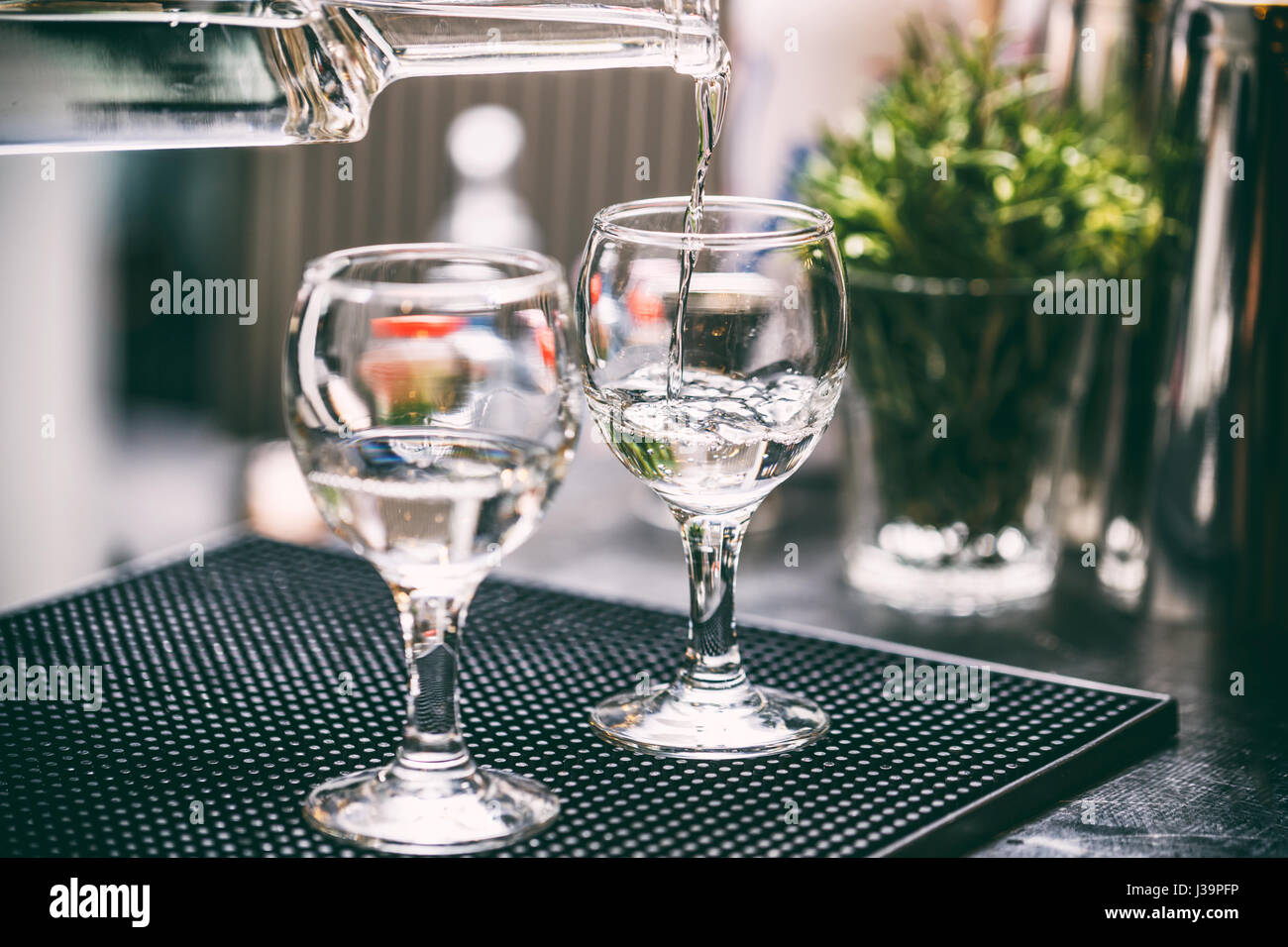 Bartender serving alcohol drinks behind bar counter. Stock Photo