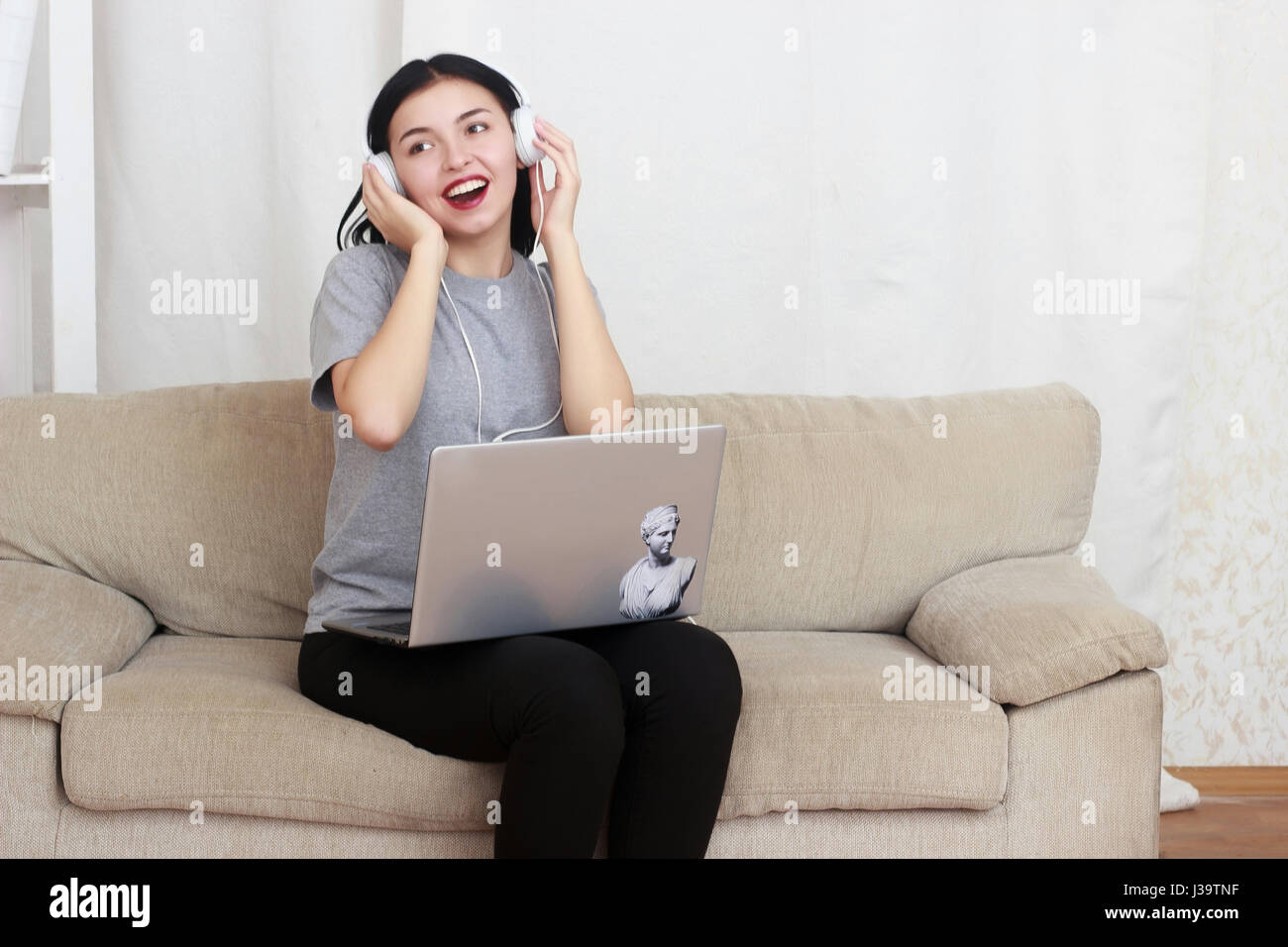 woman using laptop computer and headphones, sitting on living room Stock Photo