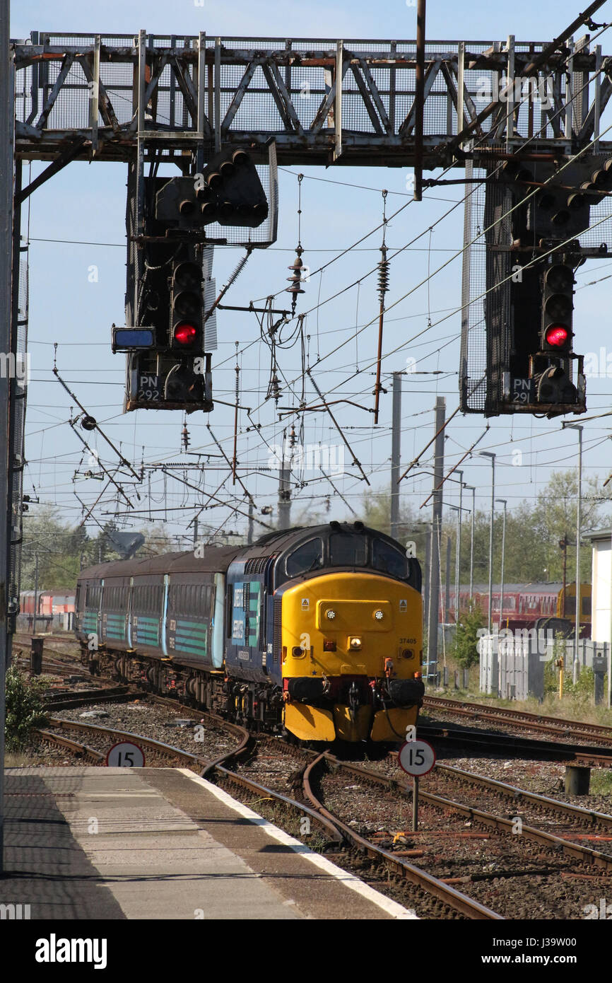 Class 37 diesel electric locomotive 37405 in DRS livery with loco hauled passenger train for Northern arriving at Carnforth railway station. Stock Photo