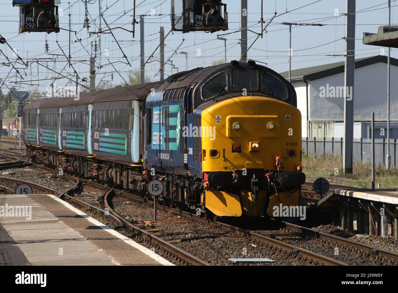 Class 37 diesel electric locomotive 37405 in DRS livery with loco hauled passenger train for Northern arriving at Carnforth railway station. Stock Photo