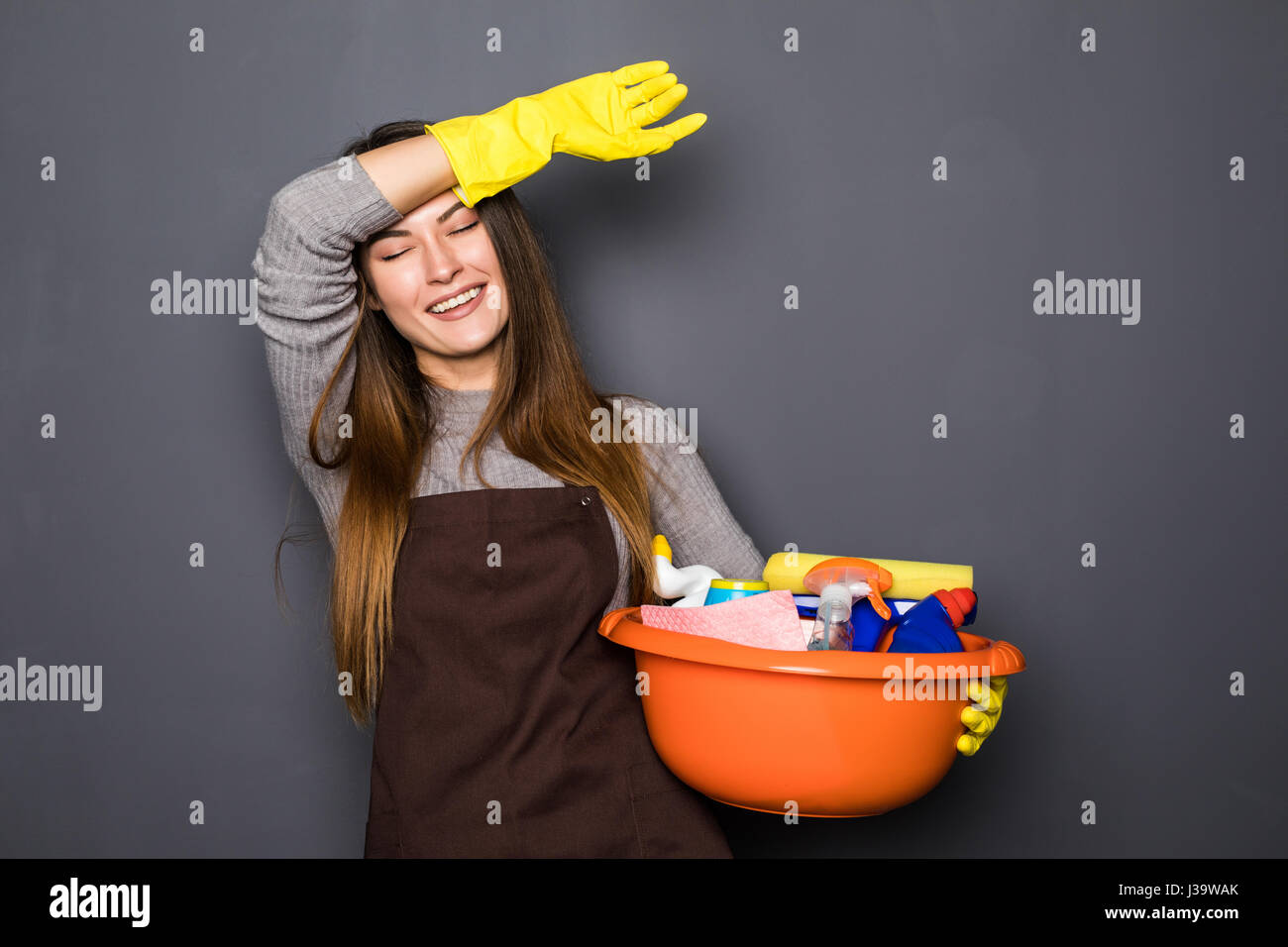 young tired woman in protective gloves holding a bucket with things for ...