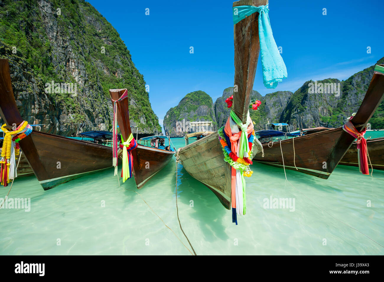 Traditional Thai wooden longtail boats with decorative sash ribbons at Maya Bay on Koh Phi Phi Leh island Stock Photo
