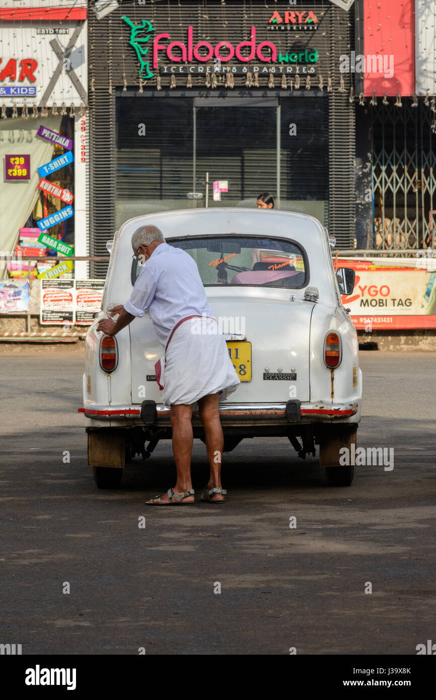 An elderly man cleans his Ambassador car in the street in Thalassery (Tellicherry), Kannur district (Cannanore), Kerala, South India, South Asia Stock Photo