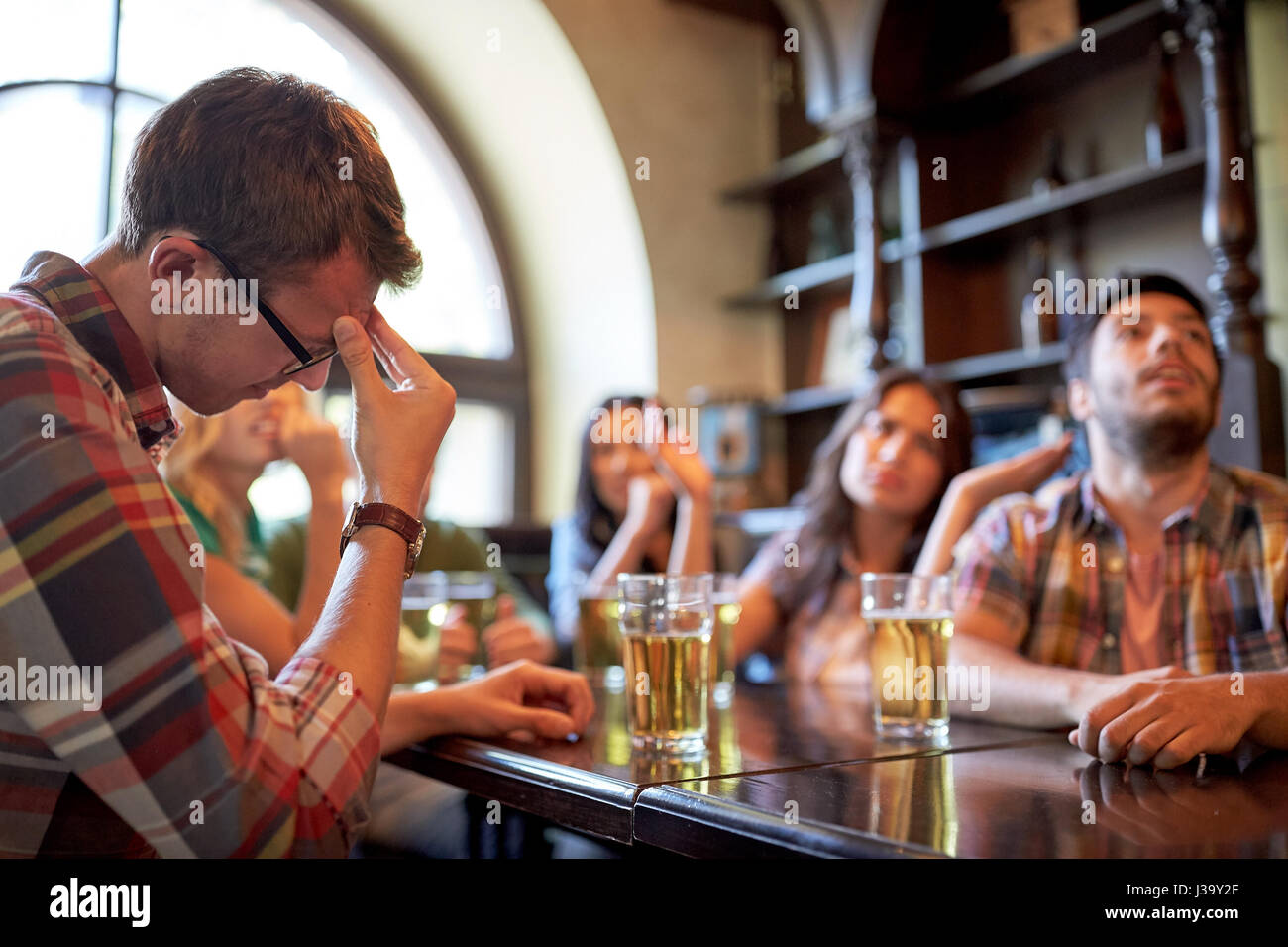 friends with beer watching football at bar or pub Stock Photo