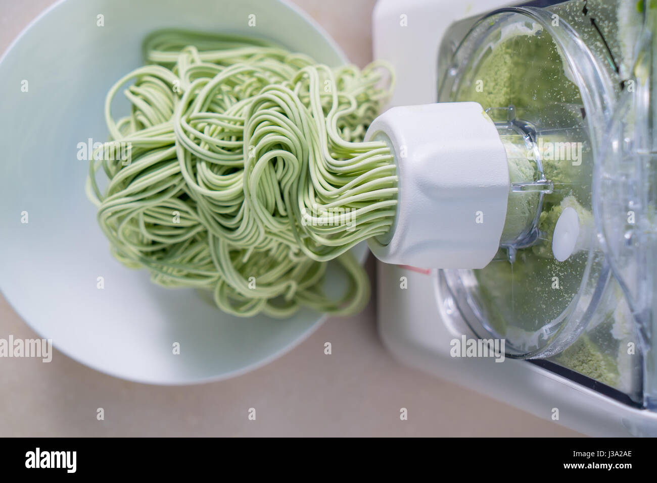 Green spaghetti pasta sheet being processed in machine Stock Photo