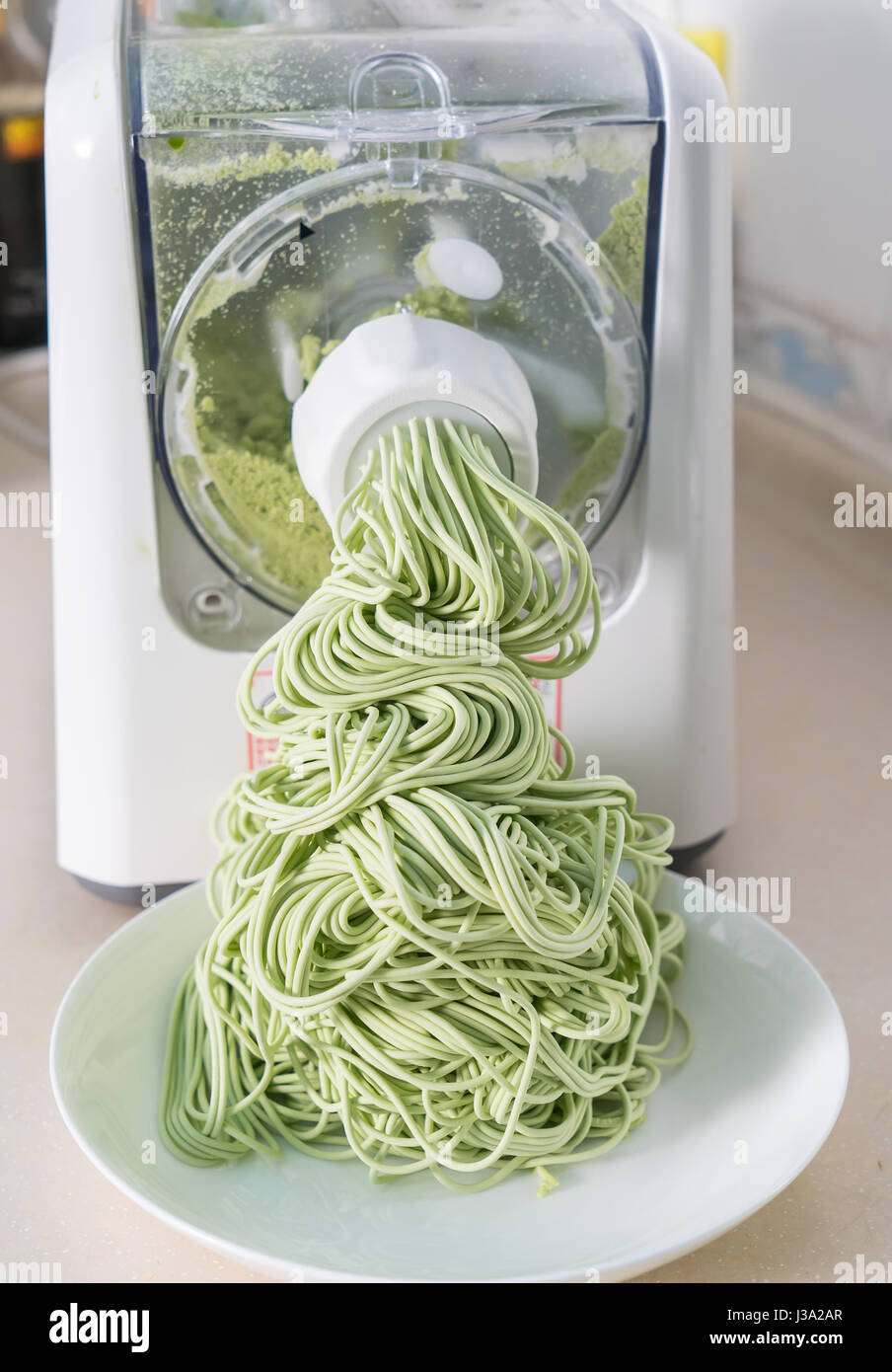 Green spaghetti pasta sheet being processed in machine Stock Photo