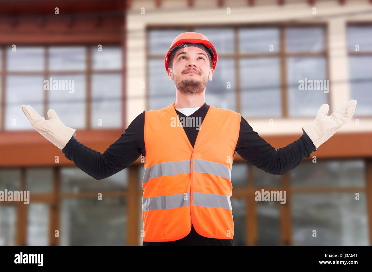 Self-confident construction worker rising his hands up as satisfaction ...