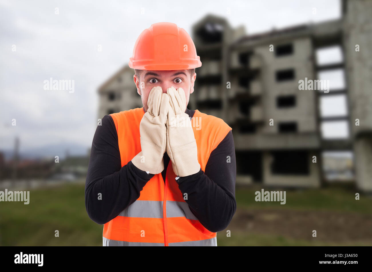 Frightened builder looking shocked after hearing the news on construction site Stock Photo
