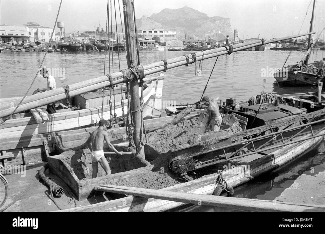 Dock workers in Palermo shoveling sand from a boat, 1963 Stock Photo