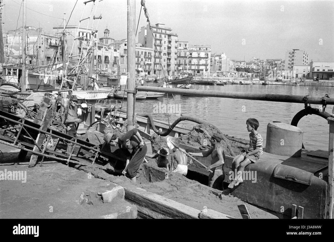 Dock workers in Palermo shoveling sand from a boat, 1963 Stock Photo