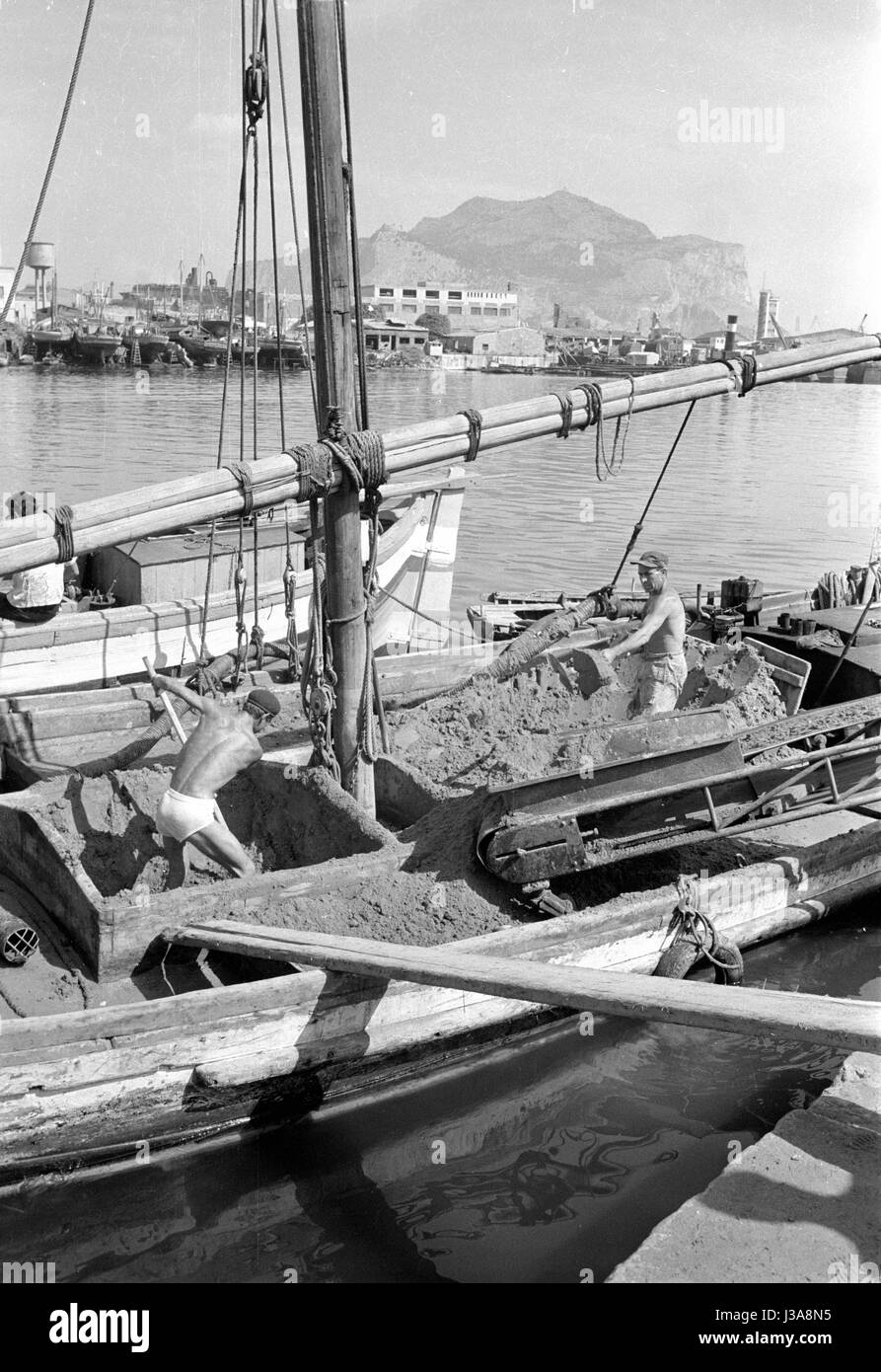 Dock workers in Palermo shoveling sand from a boat, 1963 Stock Photo