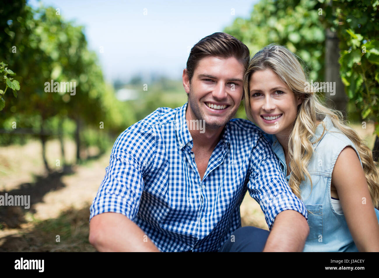Portrait of happy young couple sitting at vineyard Stock Photo - Alamy