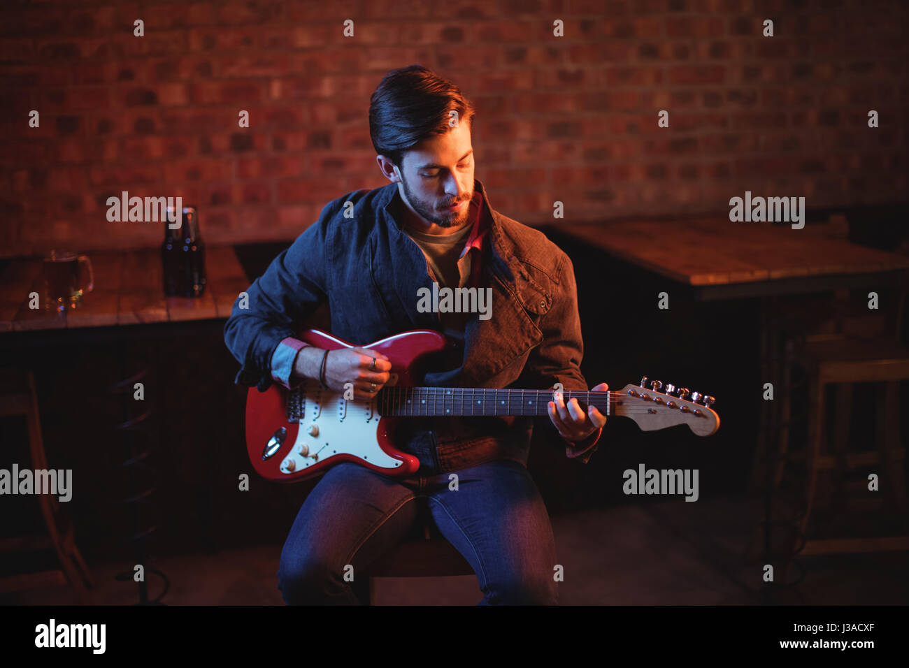 Young man playing guitar in pub Stock Photo