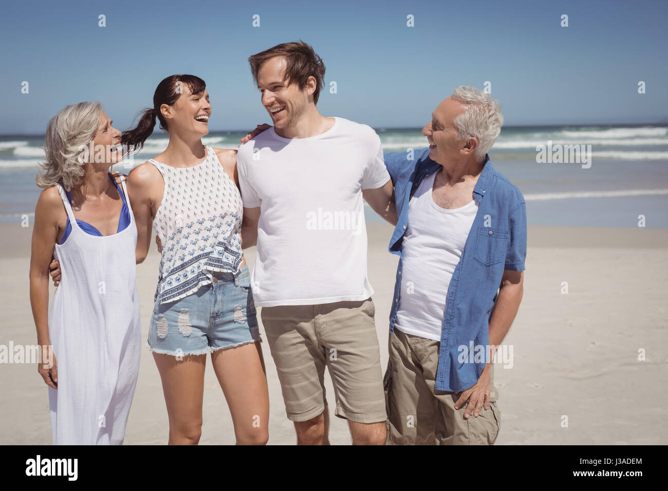 Happy family standing side by side at beach during sunny day Stock Photo
