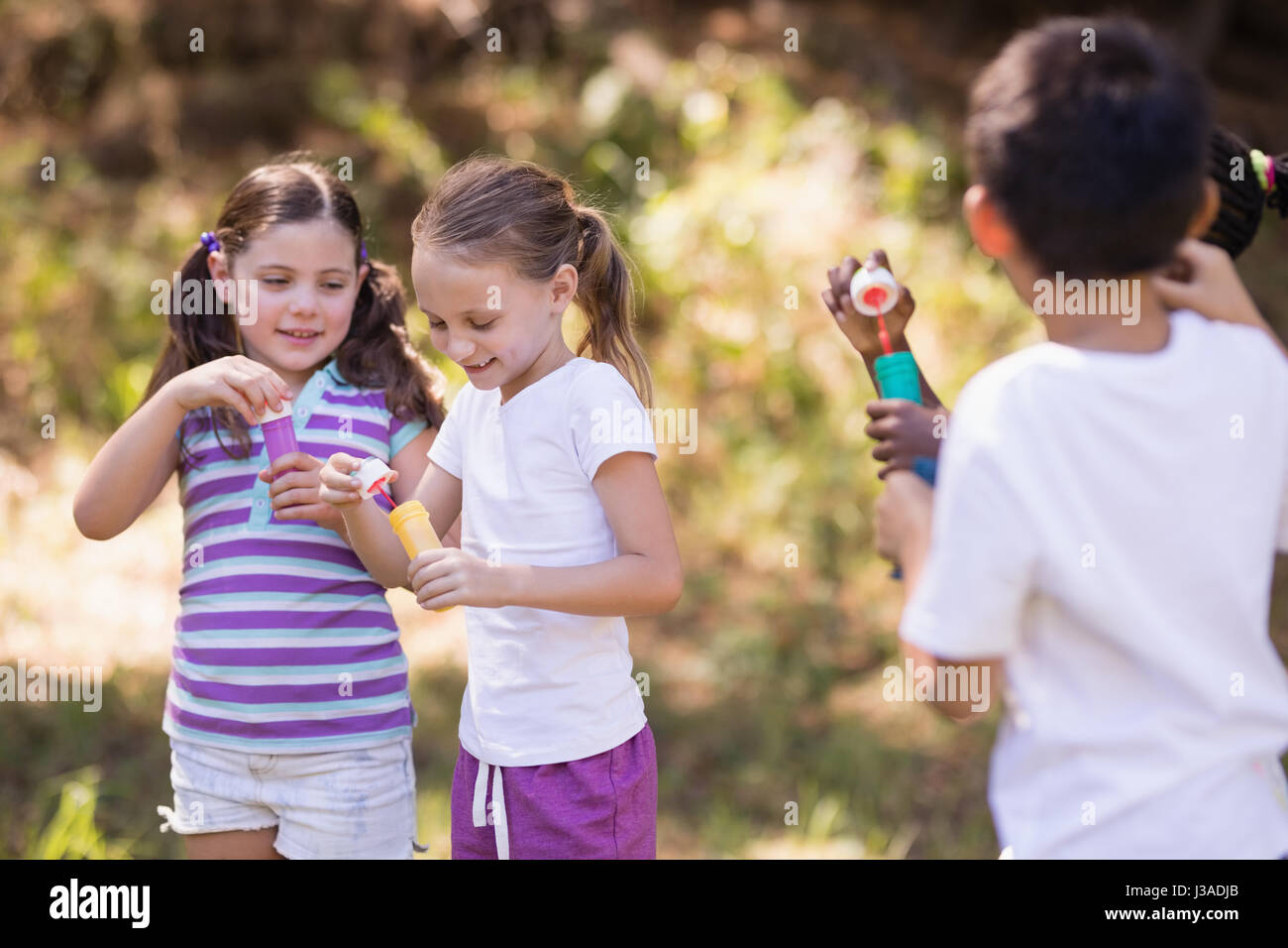 Group of friends playing with bubble wand in forest Stock Photo