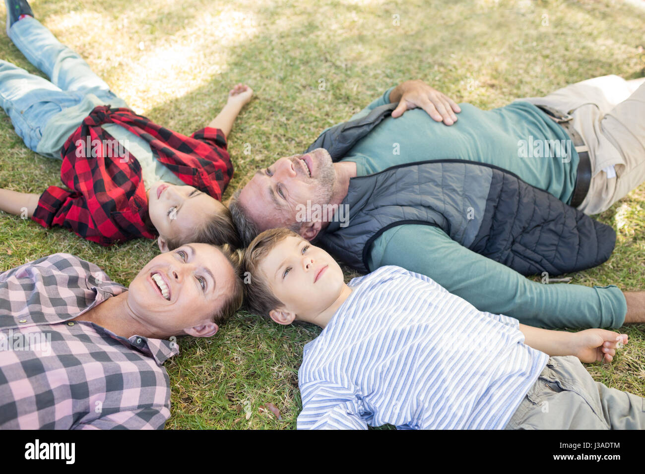 Happy family lying on the grass in park Stock Photo - Alamy
