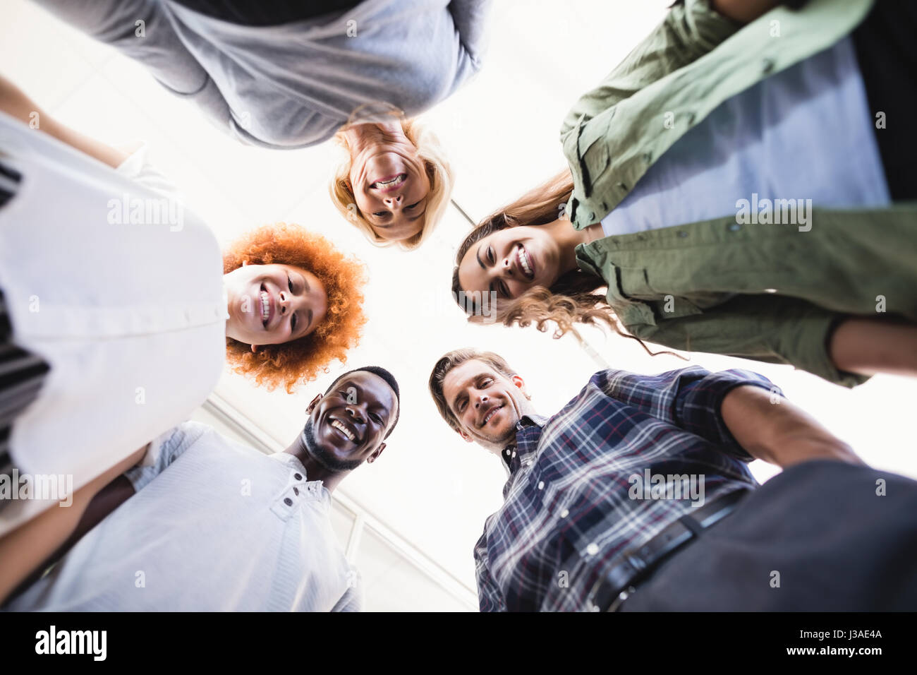 Directly below portrait of happy business people standing against ceiling in office Stock Photo