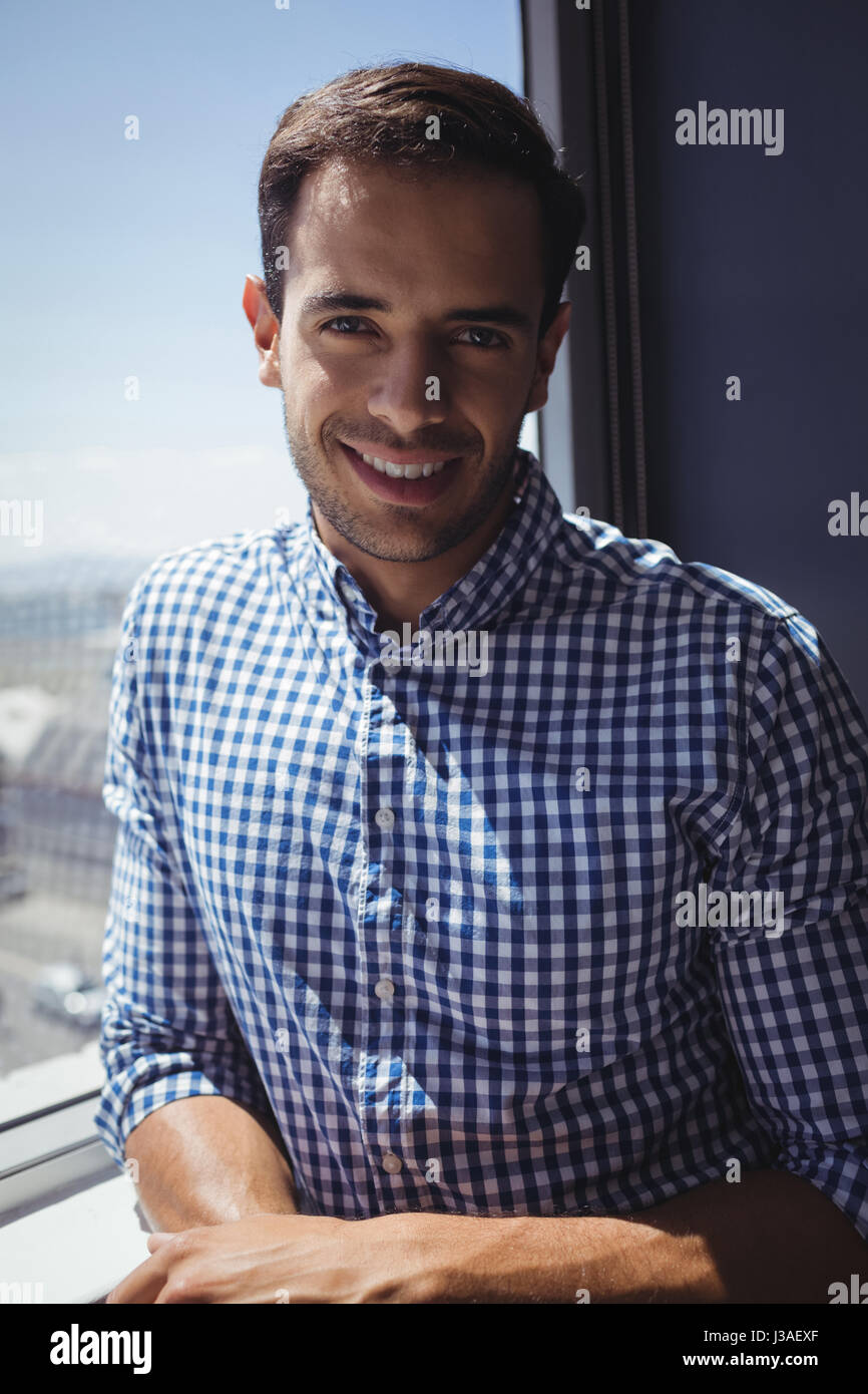 Portrait of smiling businessman standing by window in office Stock ...