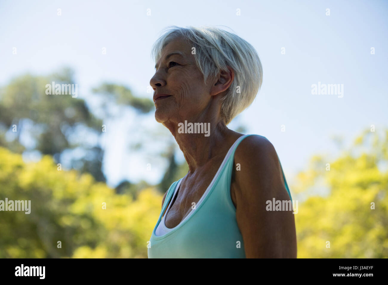 Thoughtful senior woman standing in the park Stock Photo - Alamy