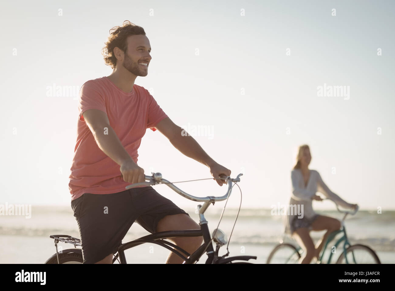 Happy Riding Happy riding bicycle at beach during sunny day Stock Photo - Alamy