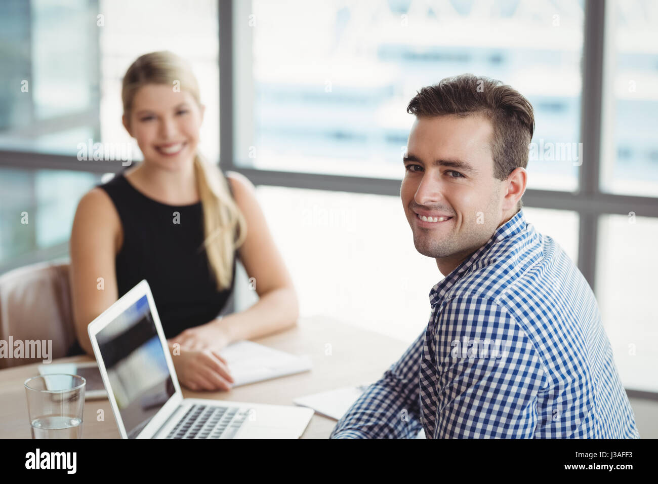 Portrait of smiling executives sitting at desk in office Stock Photo ...
