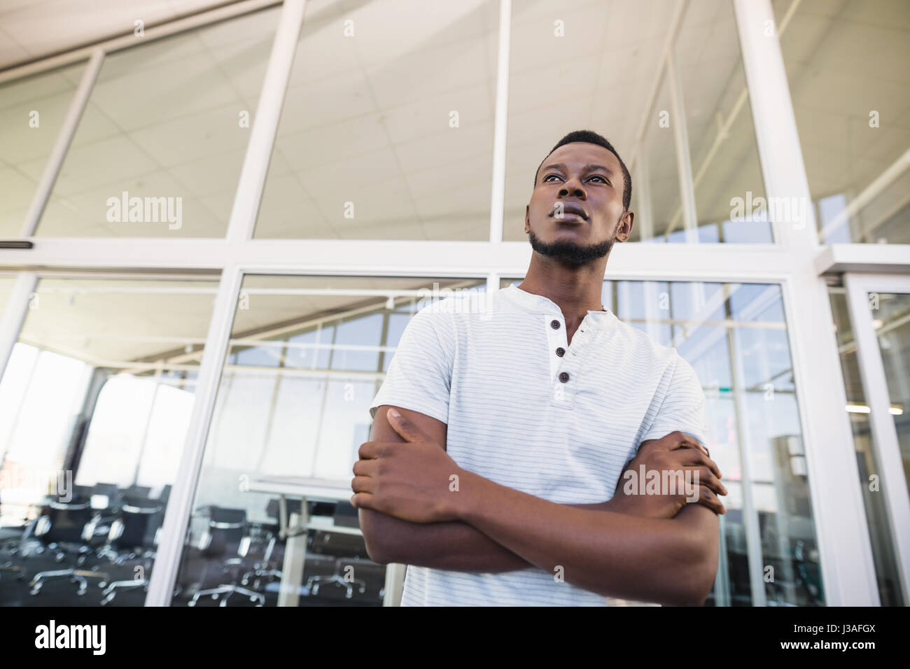 Low angle view of thoughtful businessman with arms crossed looking away ...