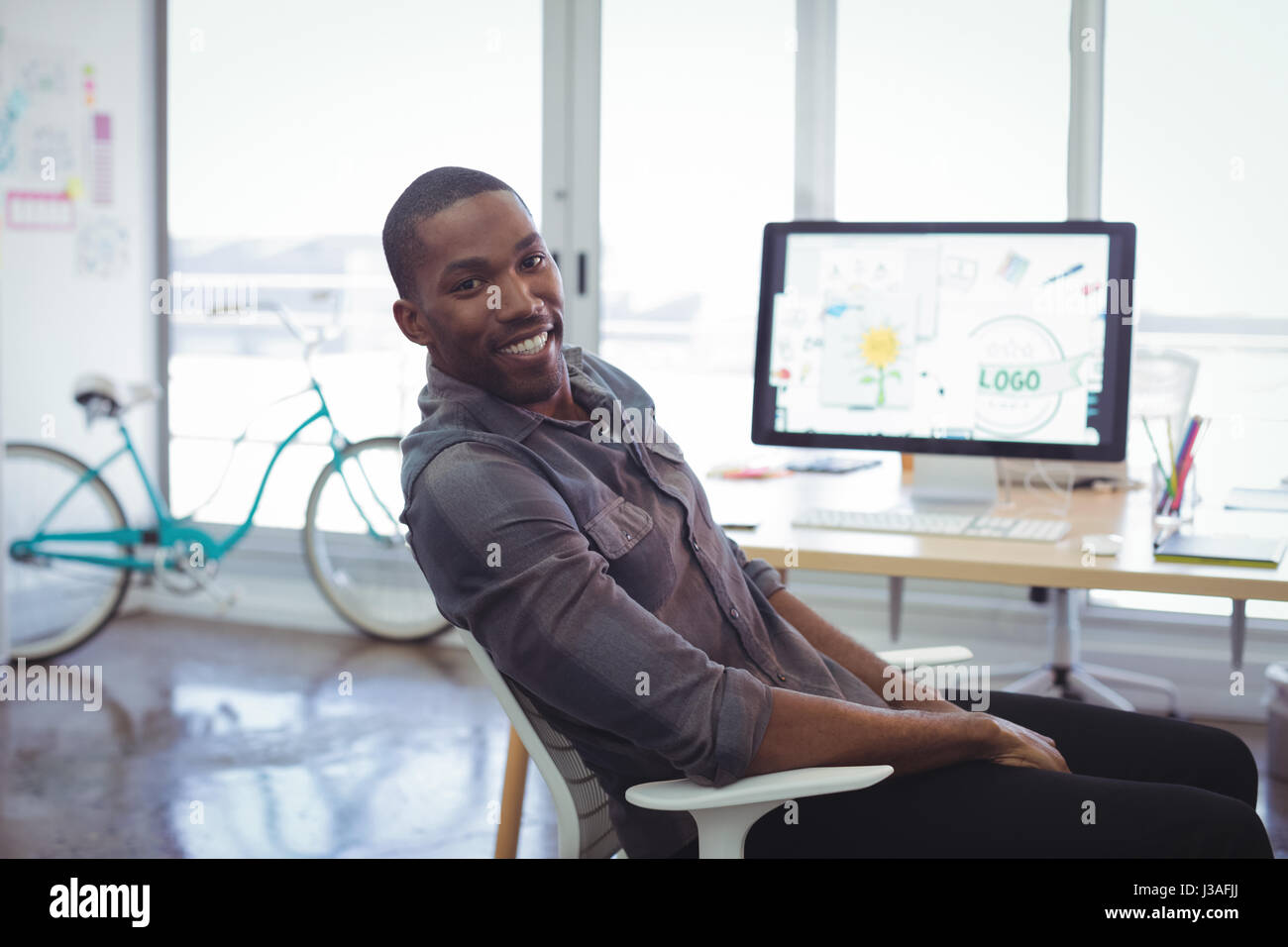 Portrait of smiling businessman sitting in brightly lit office Stock ...