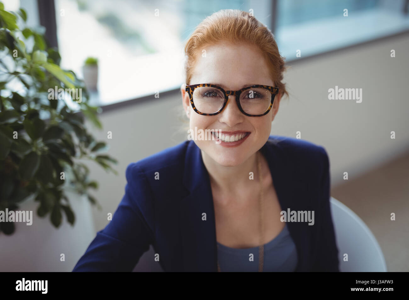 Portrait of smiling executive sitting in office Stock Photo - Alamy