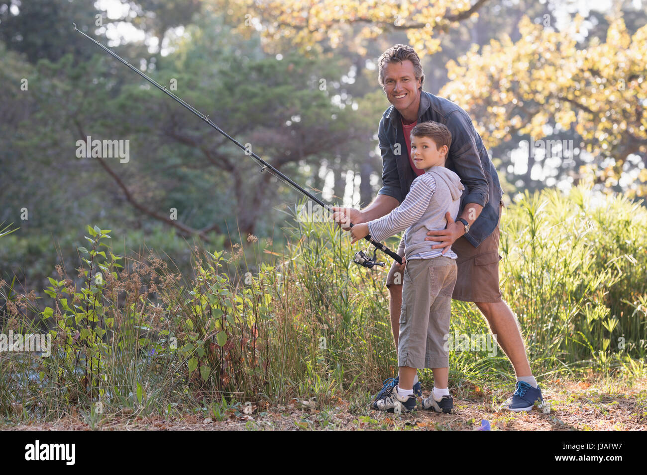 https://c8.alamy.com/comp/J3AFW7/portait-of-father-and-son-fishing-by-plants-in-forest-J3AFW7.jpg