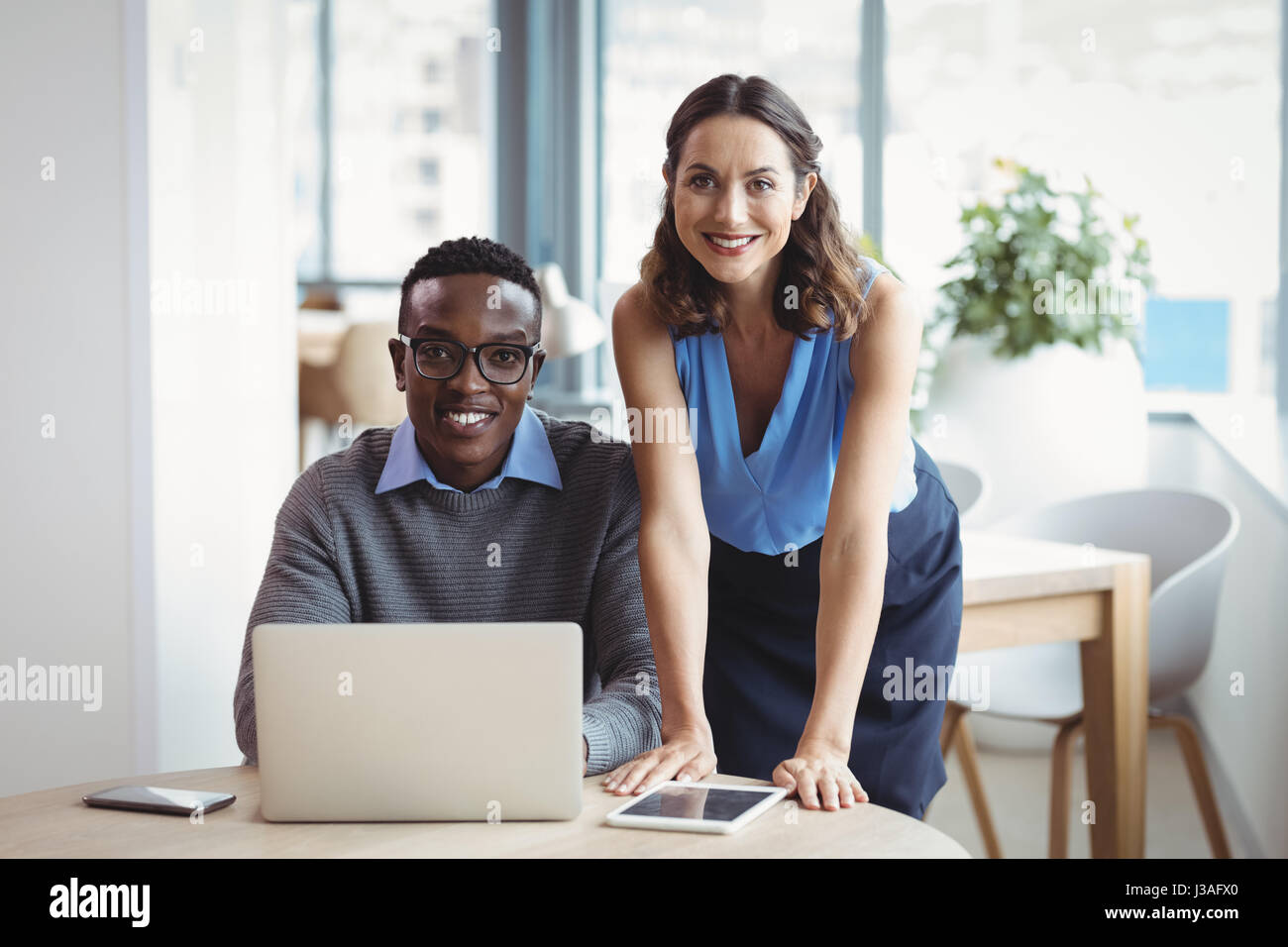 Portrait of smiling executives using laptop in office Stock Photo - Alamy