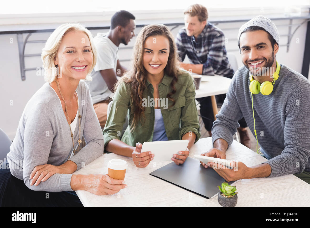 Portrait of smiling business people sitting at table in office Stock ...