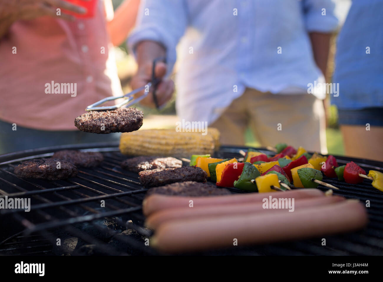 Closeup of family grilling patties, vegetables and sausages on the barbecue grill Stock Photo