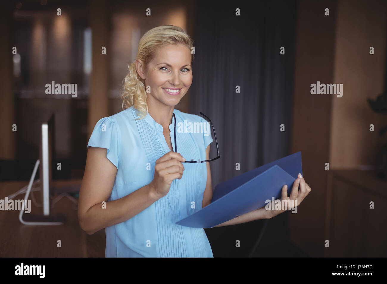 Portrait of smiling executive standing with file in office Stock Photo ...