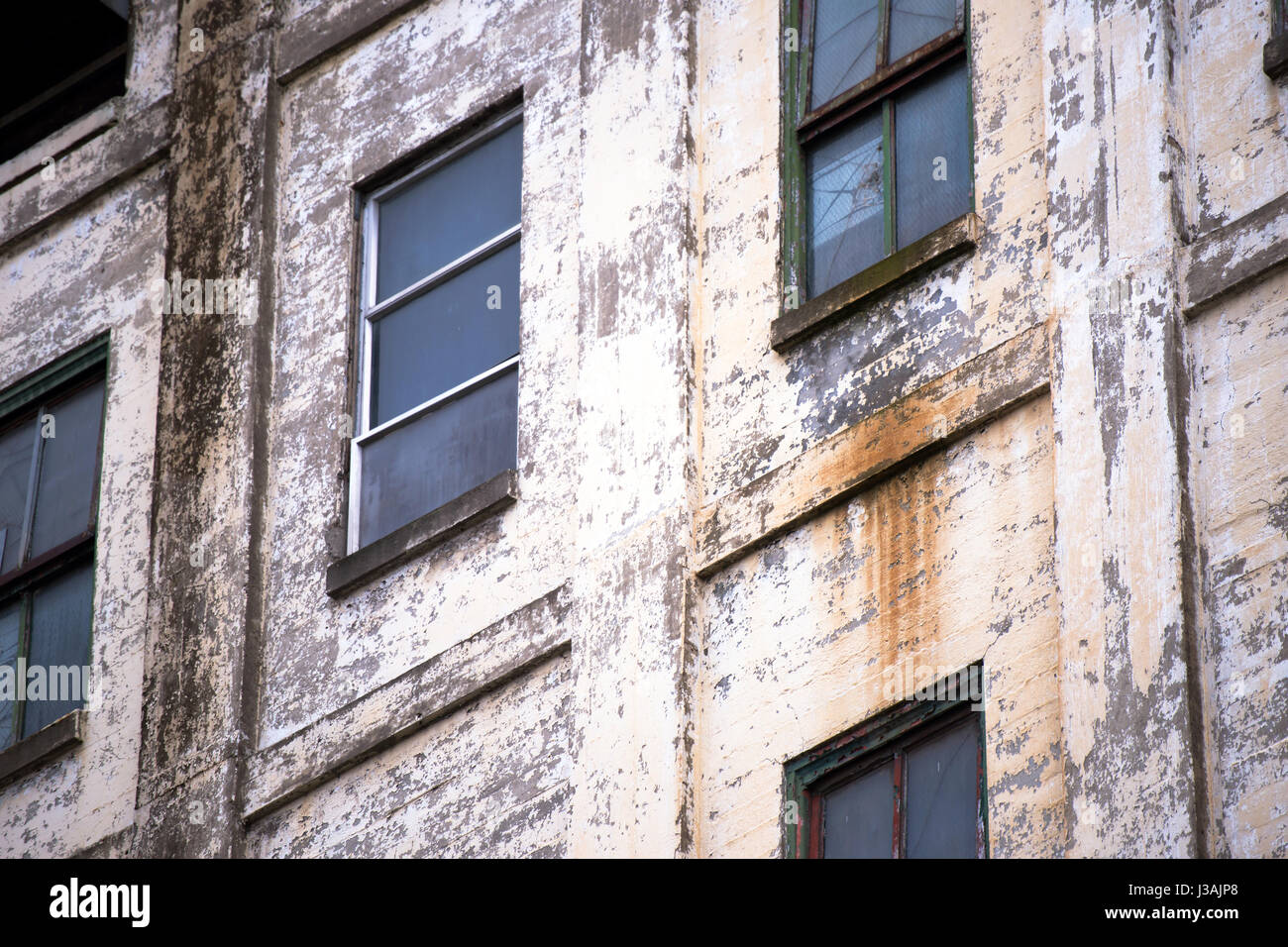 The outer wall of the old inoperative derelict abandoned multi-storey industrial building from painted bricks with rows of windows and rusted metal Stock Photo