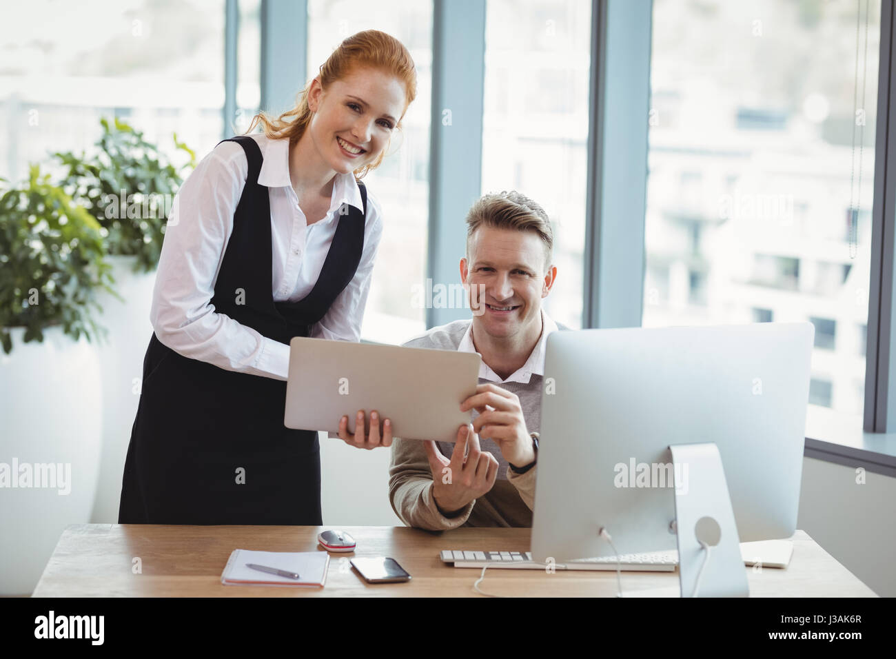 Portrait of executives using laptop at desk in office Stock Photo - Alamy